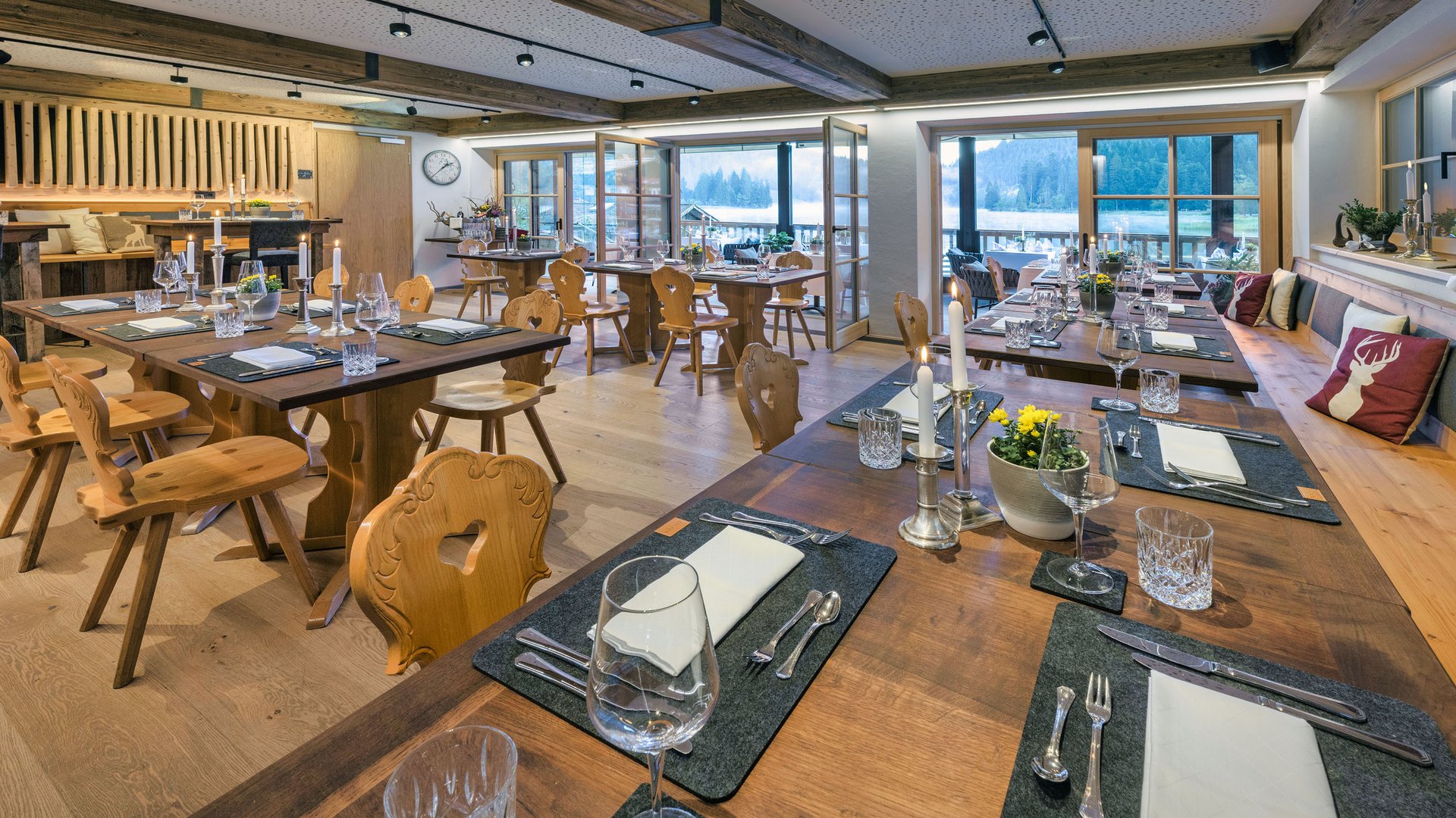 Arbeiten in der Alten Wurzhütte Gemütlich gedeckte Holztische in einem gut beleuchteten Restaurant mit Ausblick auf Berge