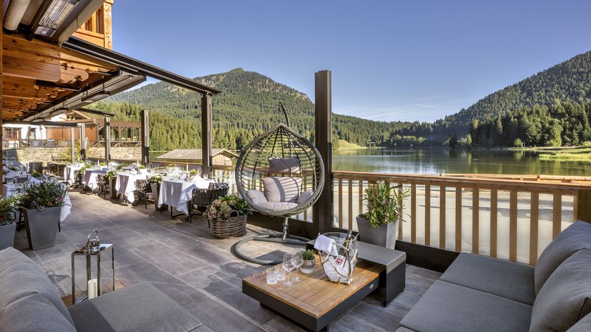 Schlemmen im Restaurant am Spitzingsee Gemütliche Terrasse mit Seeblick, Hängesessel und Tischen vor Bergkulisse