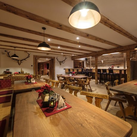 Ein Blick in die Alte Wurzhütte Rustikale Gaststube mit Holztischen, Stühlen und Hirschgeweihen an der Wand