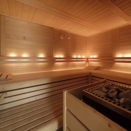 Ein Blick in die Alte Wurzhütte Helle hölzerne Sauna mit Steinofen und Beleuchtung