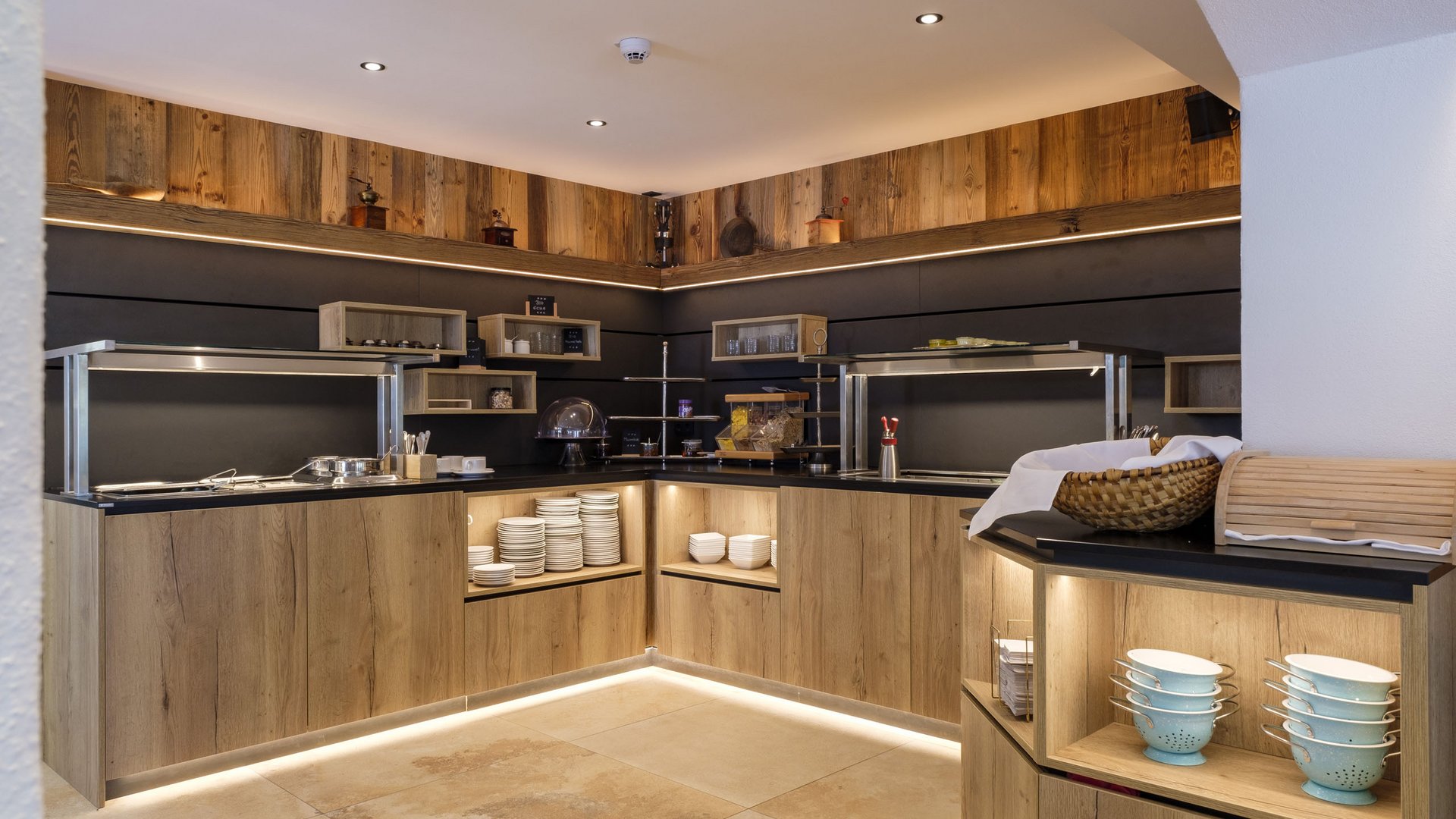 Die Verpflegung bei Tagungen Modernes Buffet mit Holzschränken, LED-Beleuchtung und Küchenutensilien