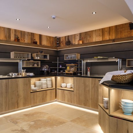 Ein Blick in die Alte Wurzhütte Modernes Buffet mit Holzschränken, LED-Beleuchtung und Küchenutensilien