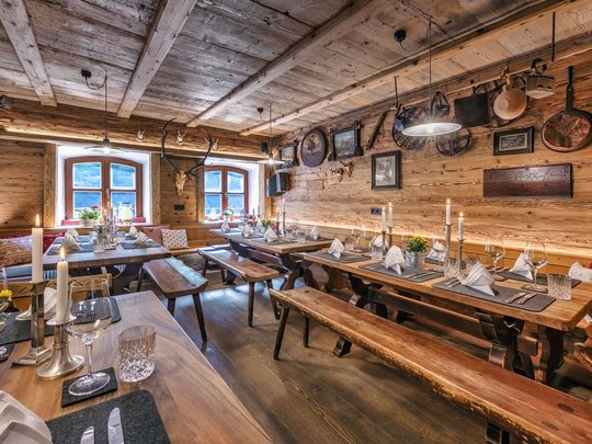 Ein Hotel mit Sauna am See? Ab in die Alte Wurzhütte! Rustikale Almhütte mit Holzinterieur und gedeckten Tischen bei Kerzenlicht