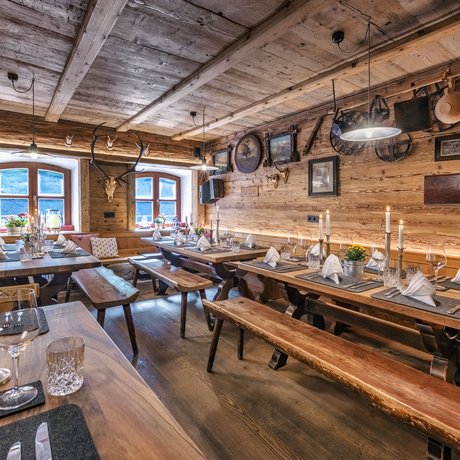Ein Blick in die Alte Wurzhütte Rustikale Almhütte mit Holzinterieur und gedeckten Tischen bei Kerzenlicht