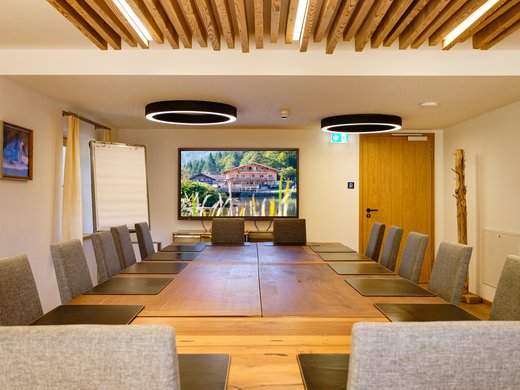 Willkommen im Tagungshotel in Oberbayern! Moderner Besprechungsraum mit hölzernem Tisch und Grauen Stühlen