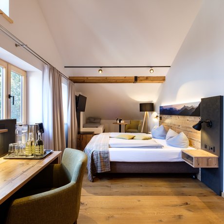 Ein Blick in die Alte Wurzhütte Gemütliches Hotelzimmer mit Holzbalken, Doppelbett und Schreibtisch