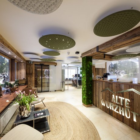Ein Blick in die Alte Wurzhütte Rezeption und Aufenthaltsbereich des Hotels Alte Wurzhütte mit Holzelementen und grüner Dekoration