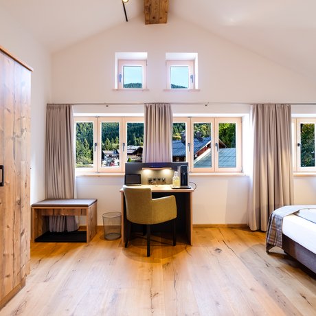 Ein Blick in die Alte Wurzhütte Hell eingerichtetes Schlafzimmer mit Fensterfront und Holzmöbeln