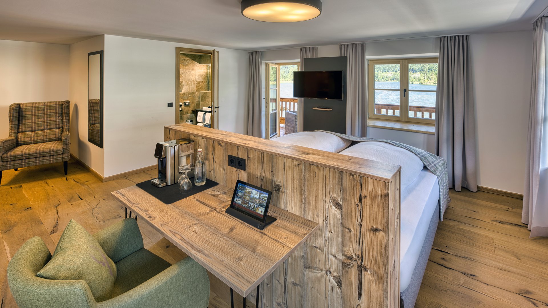 Wohlfühlen in der Unterkunft am Spitzingsee Helles Hotelzimmer mit Holzmöbeln, Schreibtisch, Sessel und Seeausblick