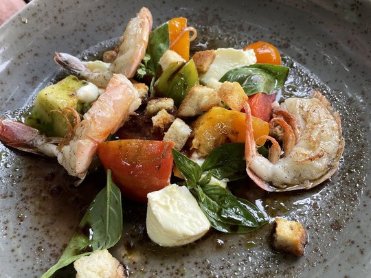 Das perfekte Menü für eure Feier Garnelensalat mit Tomaten, Mozzarella, Basilikum und Croutons auf einem grauen Teller