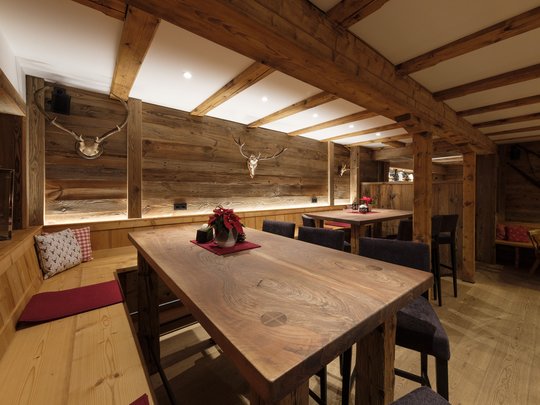 Ein Hotel mit Sauna am See? Ab in die Alte Wurzhütte! Rustikaler Gastraum mit Holztischen, Bänken und Geweihdekoration an der Wand