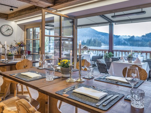 Eating at our restaurant at Lake Spitzingsee Cozy restaurant with wooden furniture and lake view through open glass wall