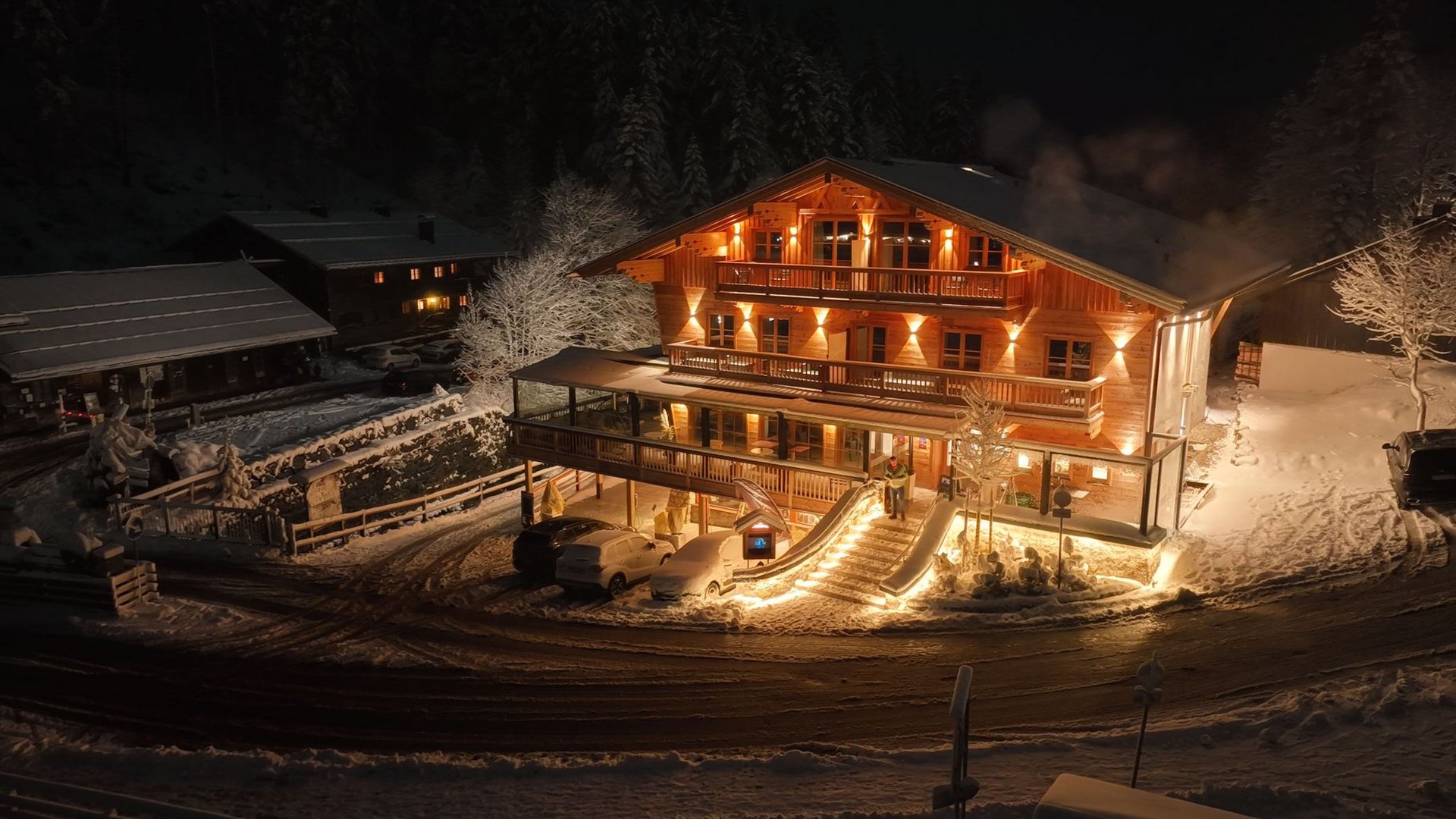 Mit einem Lächeln aufstehen im Hotel am Spitzingsee Beleuchtetes Holzhaus im verschneiten Winter bei Nacht
