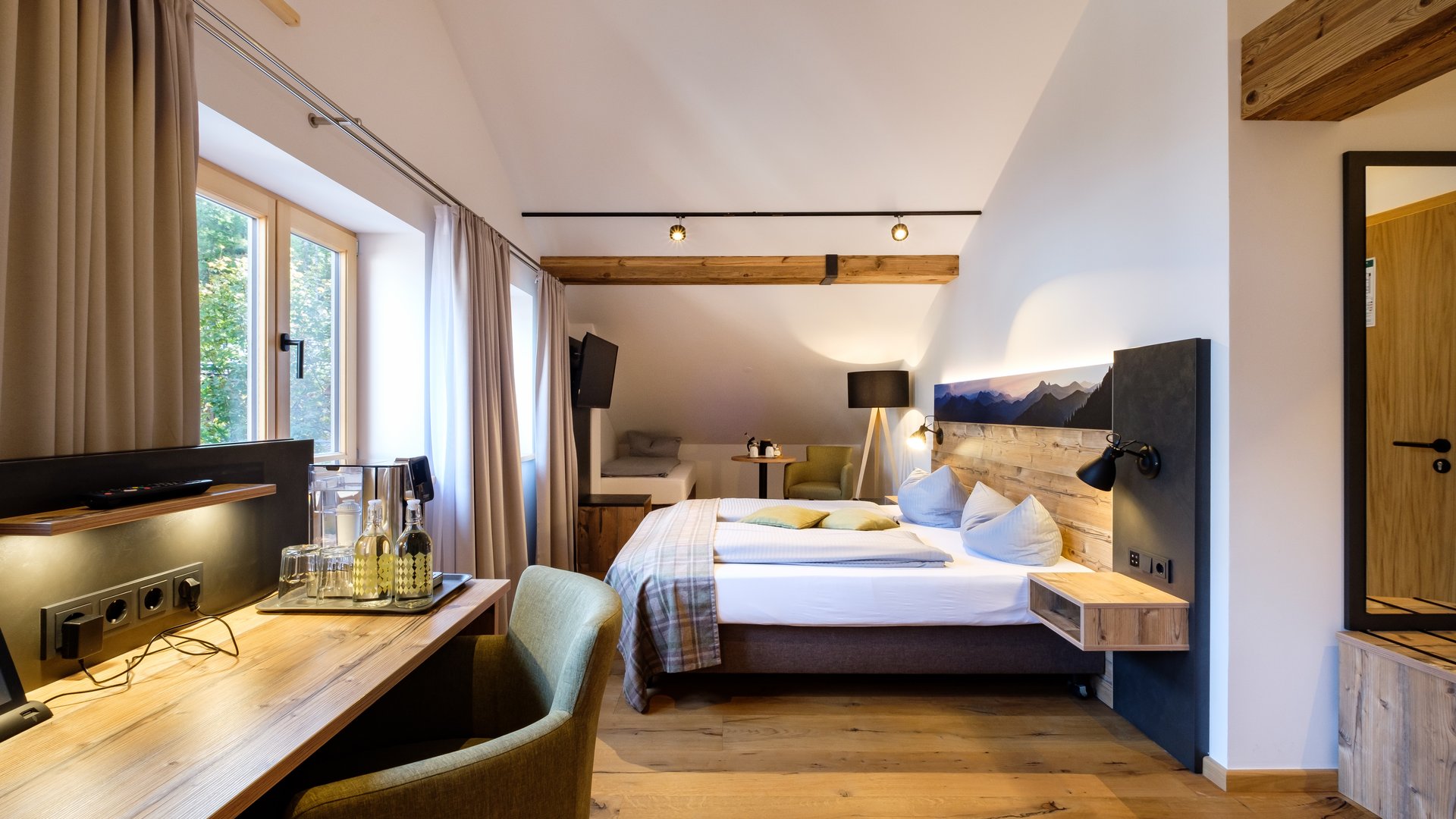 Mit einem Lächeln aufstehen im Hotel am Spitzingsee Gemütliches Hotelzimmer mit Holzbalken, Doppelbett und Schreibtisch