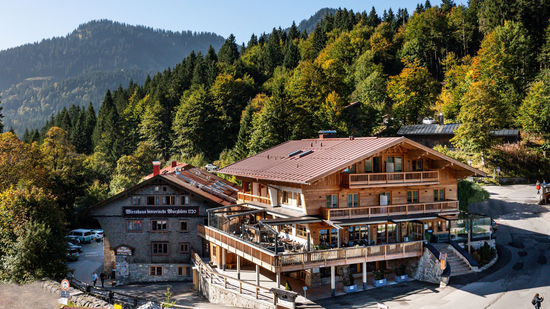Mit einem Lächeln aufstehen im Hotel am Spitzingsee Historische Würzbütte-Gaststätte in den Bergen umgeben von Wald und blauem Himmel