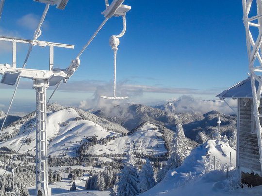 Mit einem Lächeln aufstehen im Hotel am Spitzingsee Verschneites Skigebiet mit Sessellift und Berglandschaft bei klarem Himmel